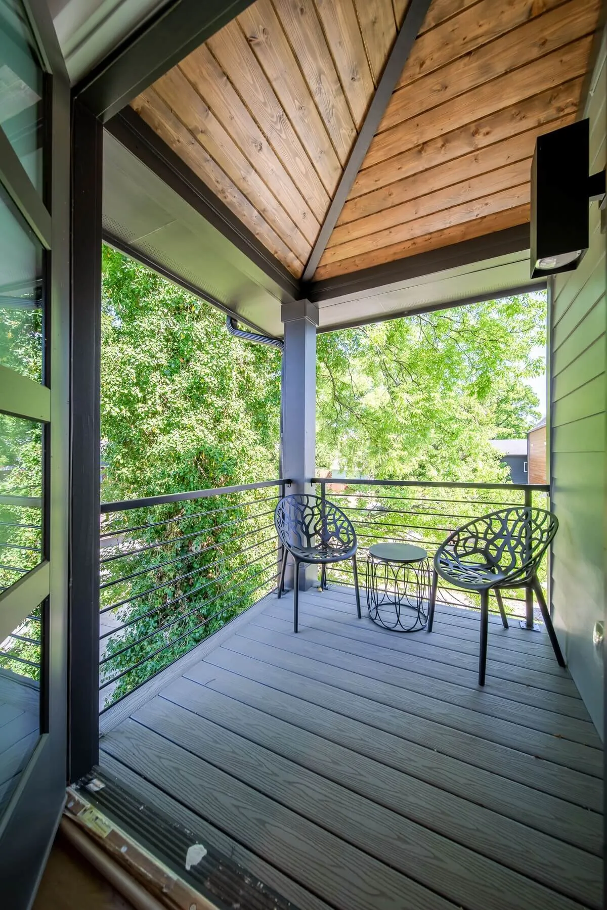A charming bistro table with decorative chairs nestled amid lush greenery, suggesting a serene, intimate spot to enjoy a morning coffee or relaxing conversation. The ambiance is peaceful and private, ideal for quiet escapes or social moments in an outdoor setting.