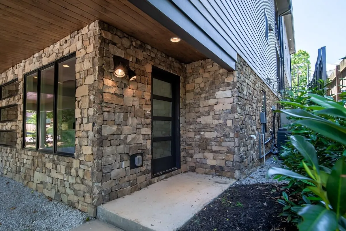 The image highlights the modern exterior facade of the home, with a striking stone finish, welcoming door, and a neat landscaped border. It captures the inviting and stylish essence of Sojourners Haven, setting an elegant tone for group events.