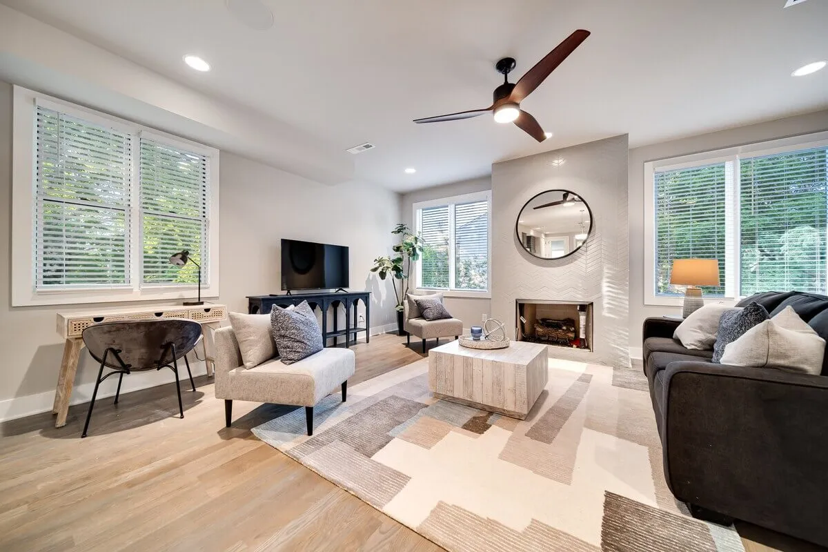 A bright, inviting living room featuring a plush sofa, stylish coffee table, large TV, lush houseplant, and ample natural light streaming in through expansive windows. The room exudes comfort and is perfect for relaxing, socializing, or gathering with friends and family.